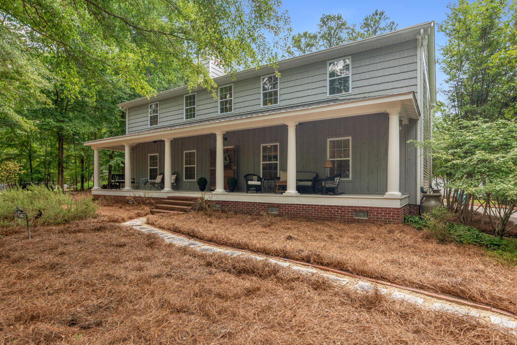Two-story gray house with a furnished covered porch and a stone path across the front yard.