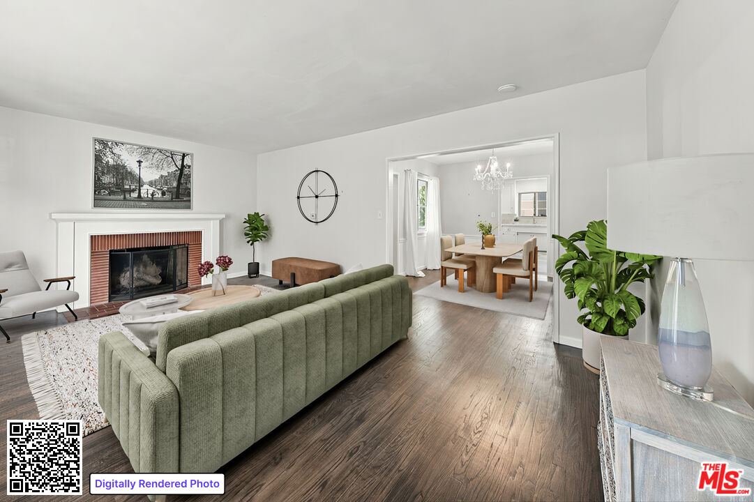 Staged living room with a green sectional, white fireplace, and adjoining dining area.