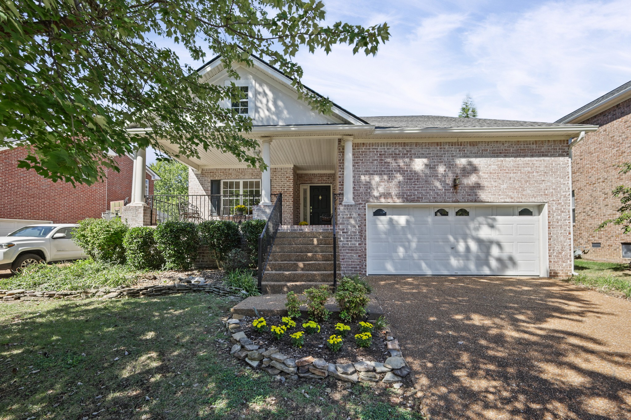 Brick home with a covered porch, double garage, and stone-edged flower bed.
