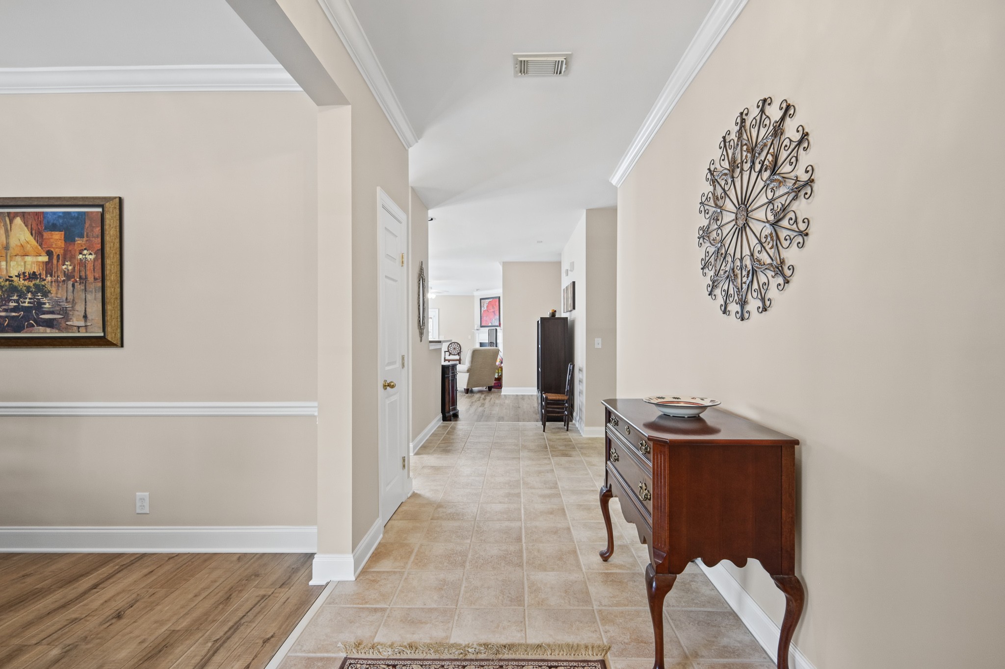 Tiled entryway with a dark wood console table and a hallway leading into the home.