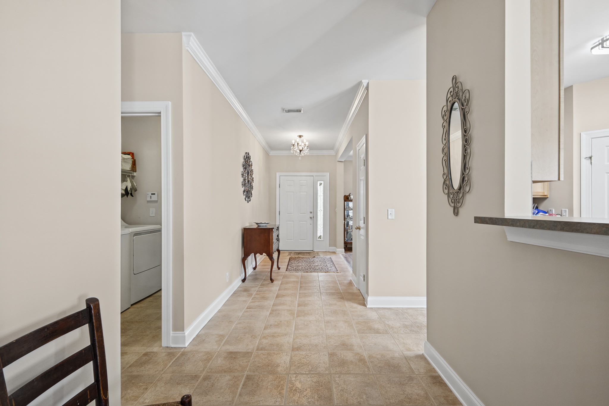 Entry hall with tan tile flooring, a chandelier, and a front door with a glass sidelight.