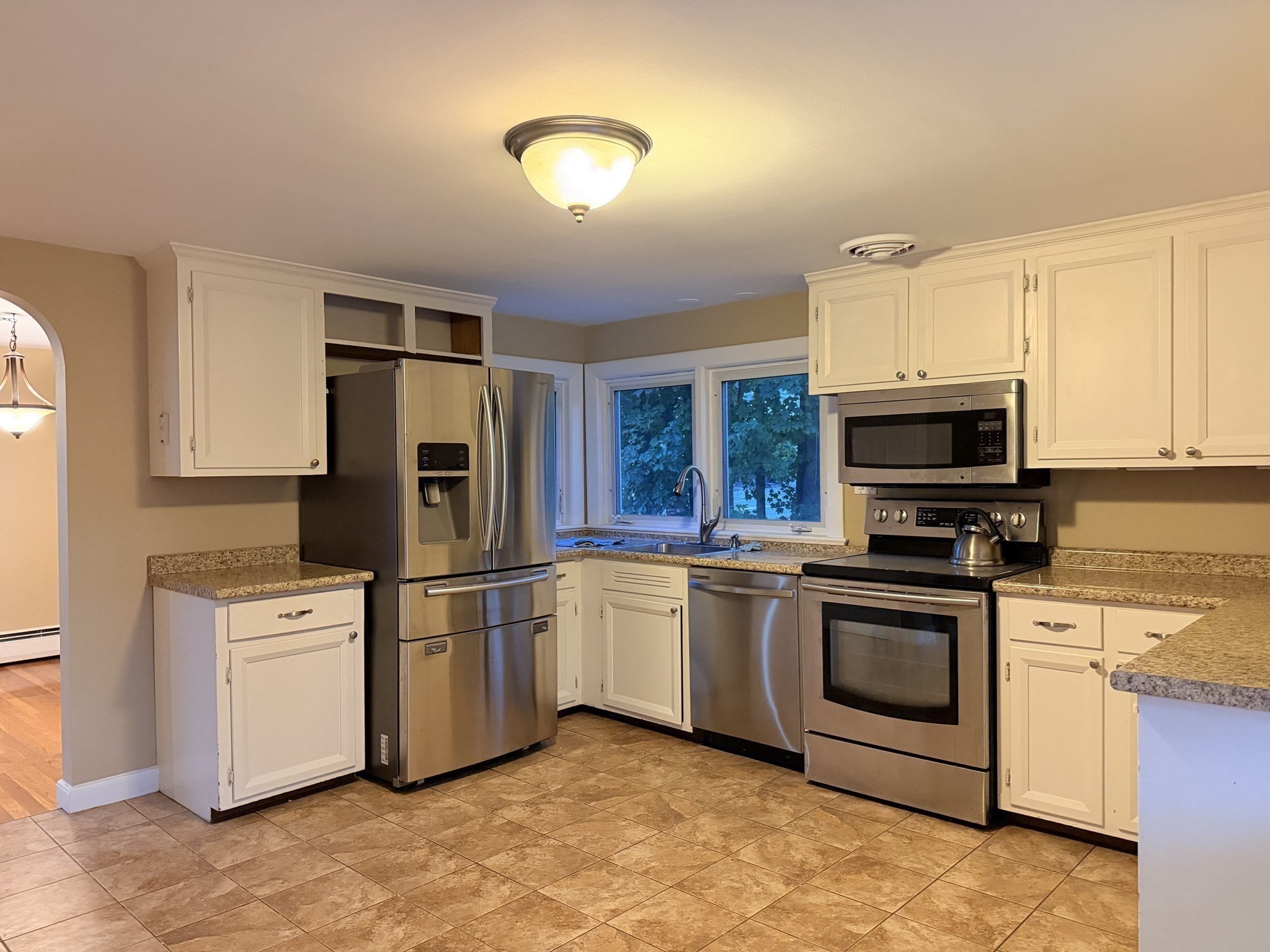 Kitchen with white cabinets, granite counters, stainless steel appliances, and two windows above the sink.