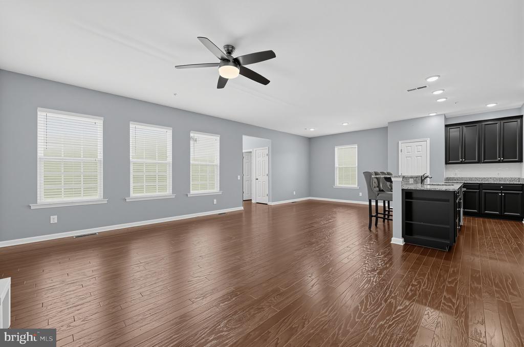 Open living area with brown hardwood floors, gray walls, and a black kitchen island.