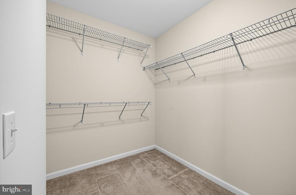 Walk-in closet with wire shelving on three walls and beige carpet.