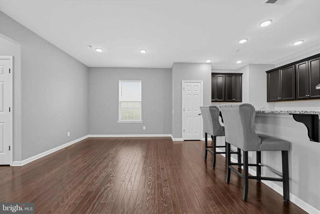 Finished room with dark wood floors, gray walls, and a counter with two upholstered bar stools.