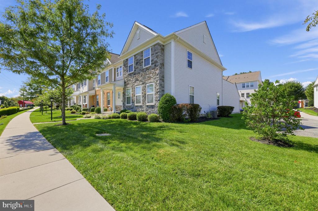 Townhouse exterior with a stone facade, landscaped lawn, and sidewalk.