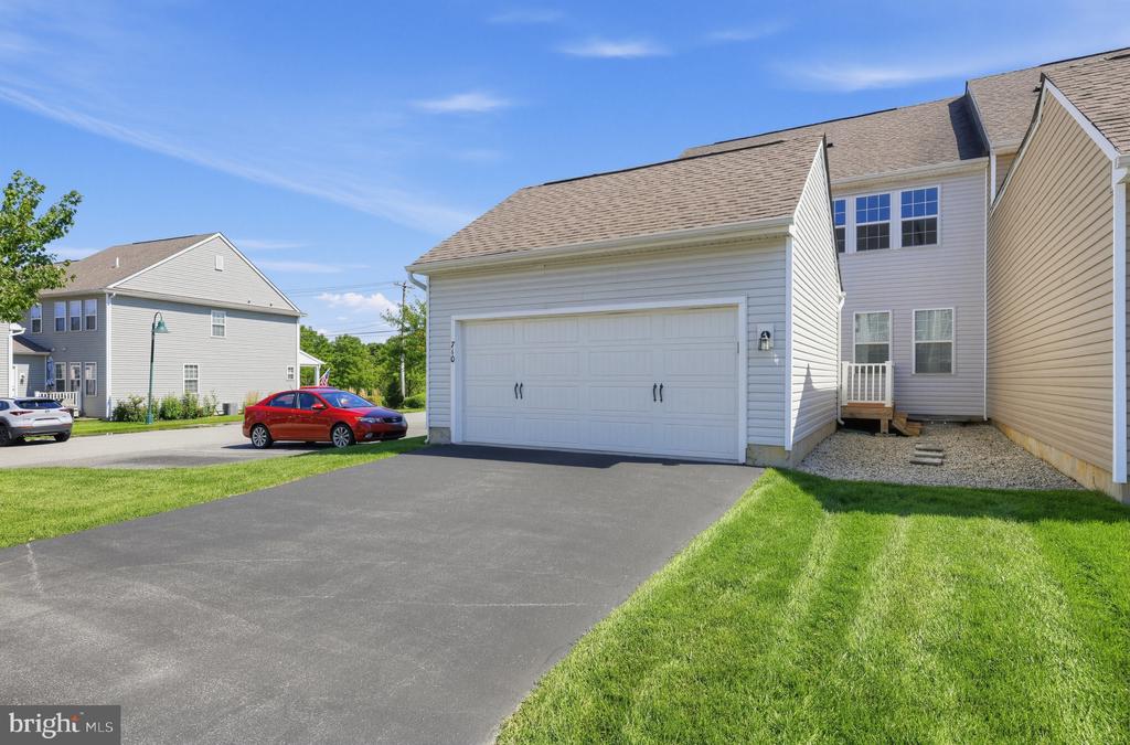 Two-story home with an attached two-car garage, broad driveway, and green lawn.