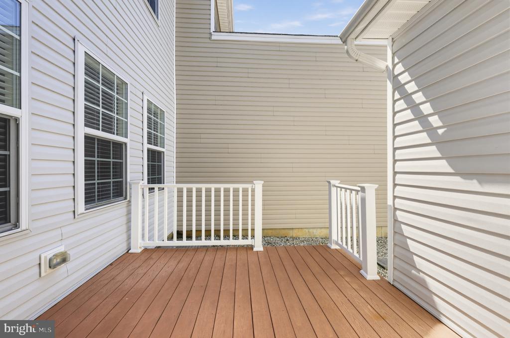 Deck with reddish-brown flooring, white railings, and light-colored siding.