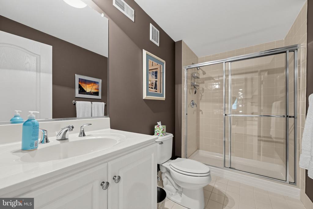 Bathroom with a white vanity and toilet beside a glass-enclosed tiled shower.