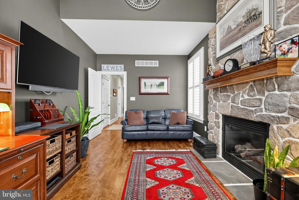 Living room with a blue leather sofa, red patterned rug, and stone fireplace.