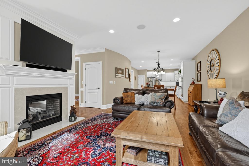 Furnished living room with a white fireplace, leather sofas, and an open view to the kitchen.