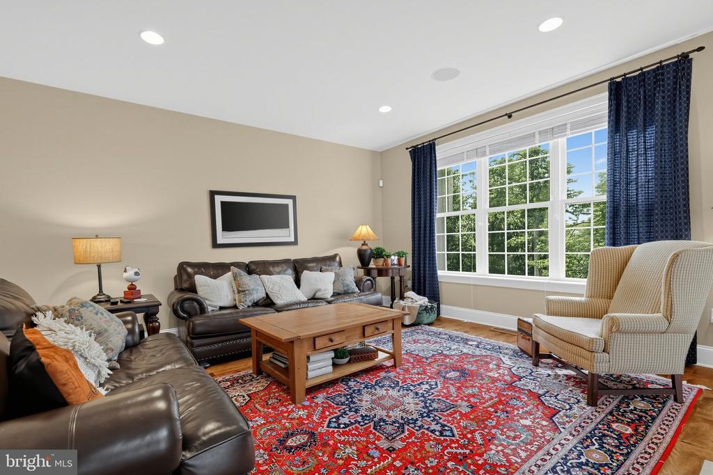 Living room with leather sofas, a red patterned rug, and a large window overlooking trees.