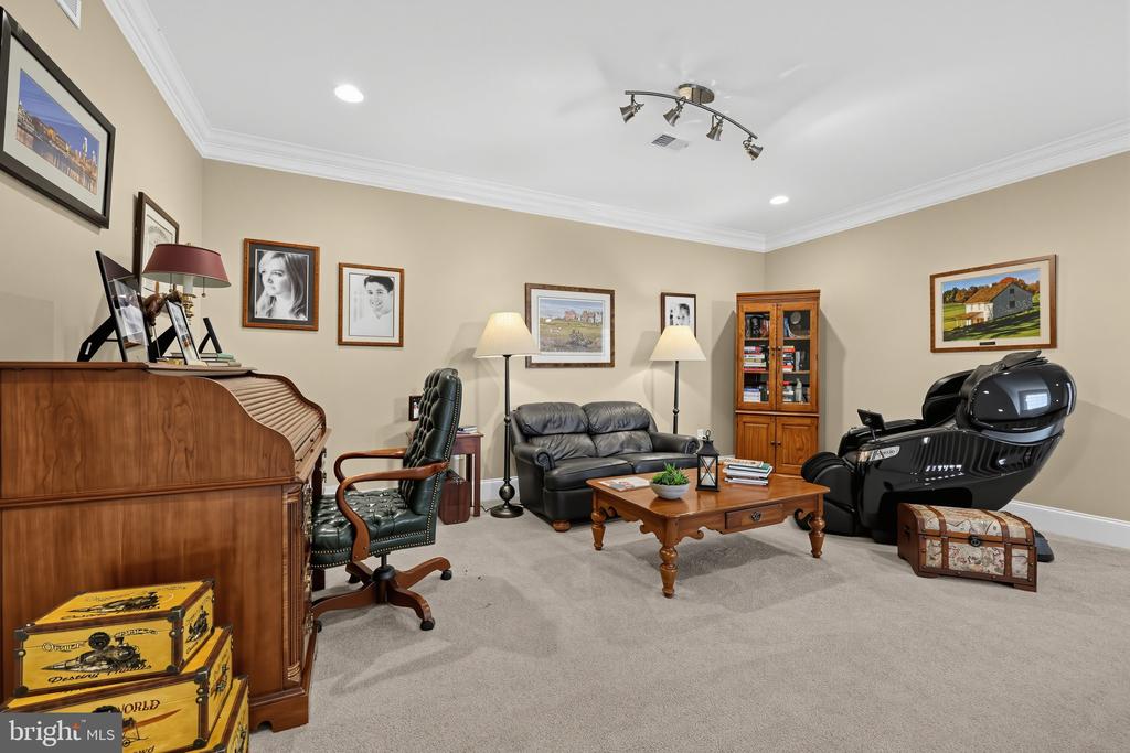 Furnished entertainment room with a piano, leather sofa, and black massage chair.