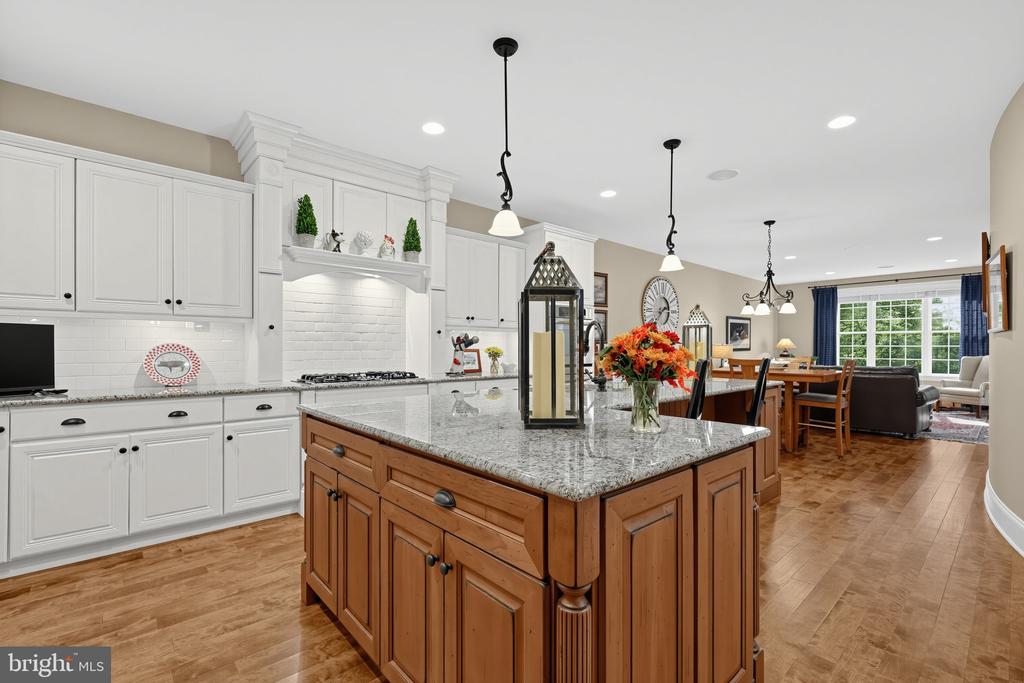 Kitchen with white cabinetry, a large wood-and-granite island, and an adjoining dining and living area.