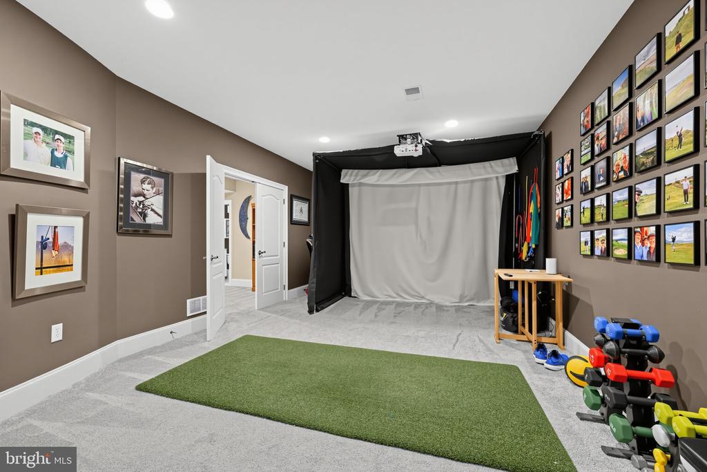 Finished studio with a white photography backdrop, green turf, exercise weights, and sports photos on the walls.