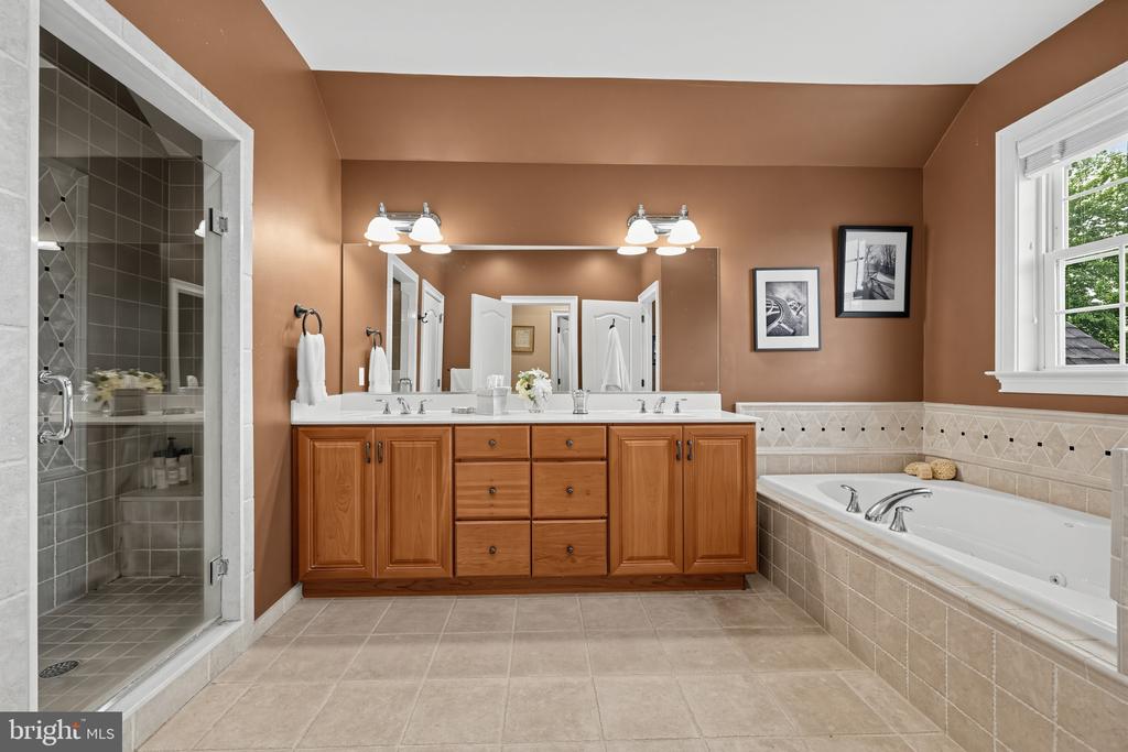 Bathroom with a double-sink wood vanity, tiled glass shower, and built-in soaking tub.