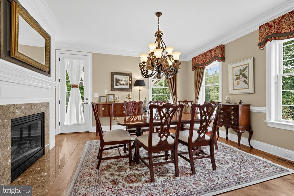 Furnished dining room with a carved wood table, ornate chandelier, and fireplace.