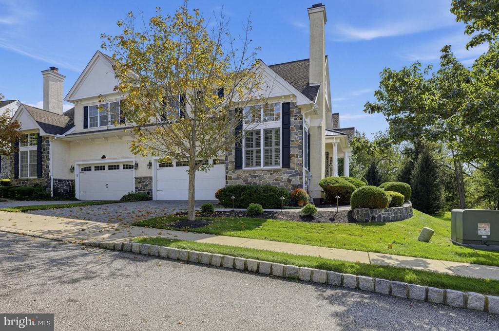 Two-story house with stone accents, twin garages, tall chimneys, and landscaped front yard.