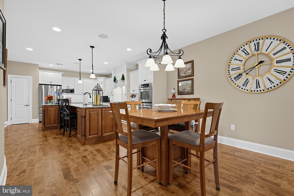 Kitchen and dining area with a wood island, white cabinetry, and a large Roman numeral wall clock.