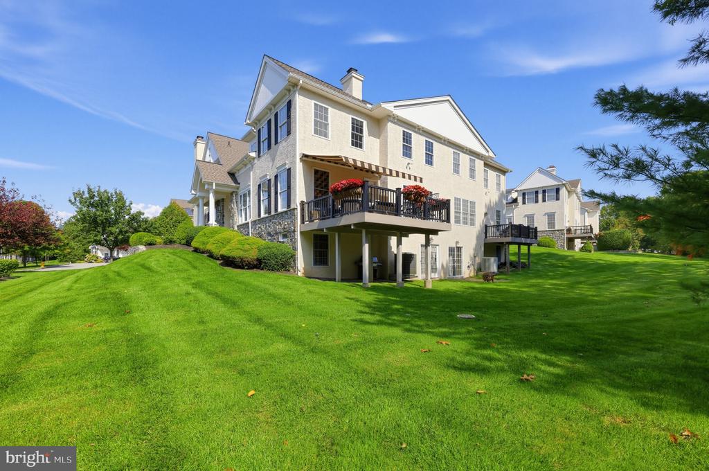 Cream-colored home with flower-decked balconies overlooking a broad green lawn.