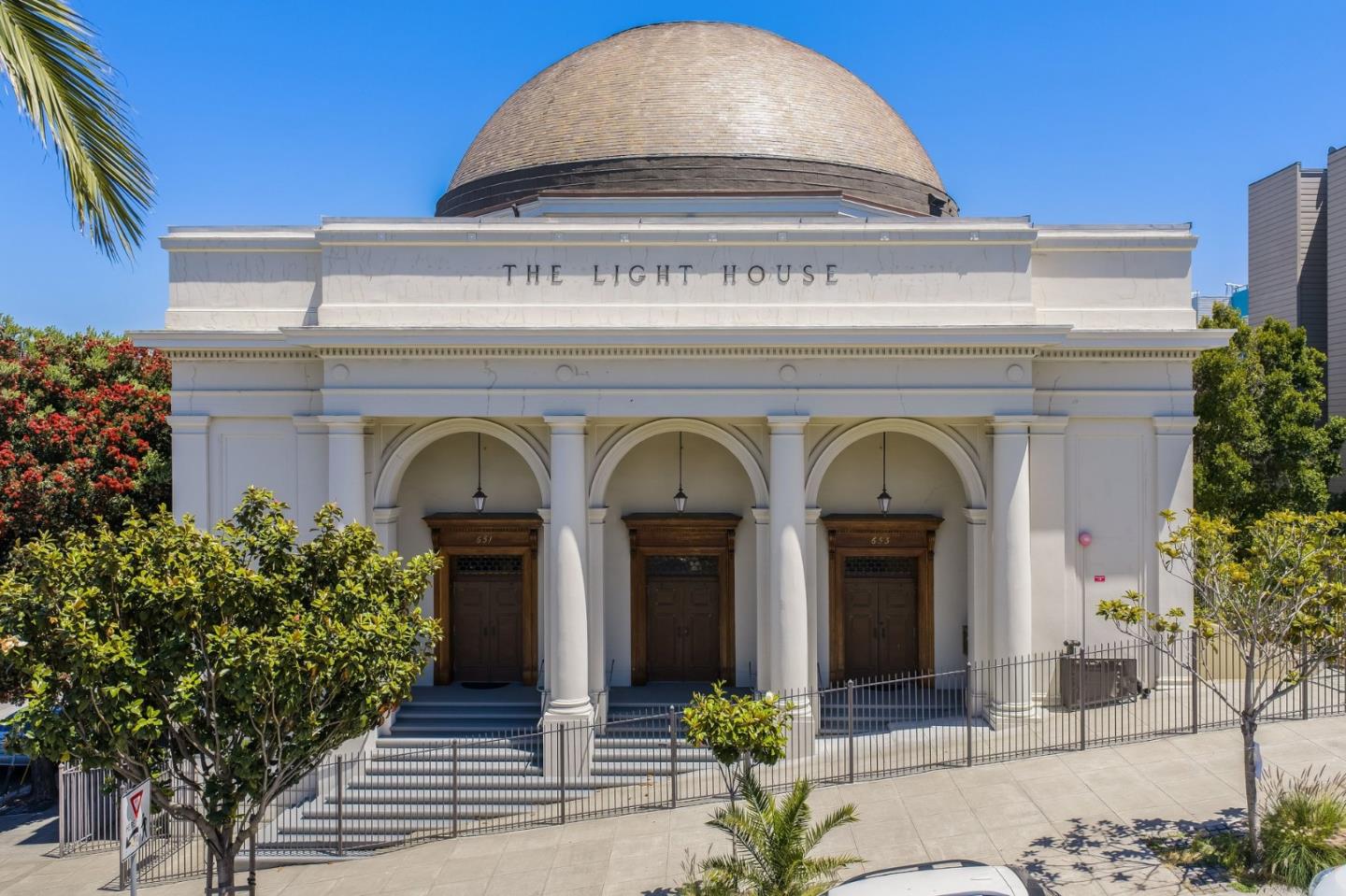 White building with a domed roof and three arched entrances beneath a THE LIGHT HOUSE sign.