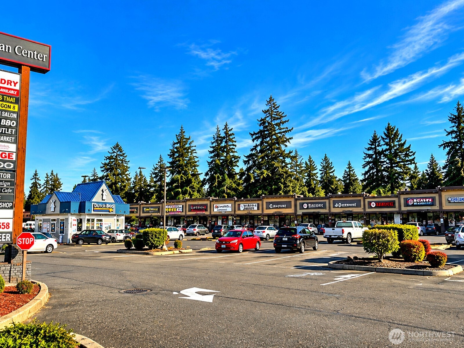 Retail strip center with a Dutch Bros coffee shop, storefronts, and a busy parking lot.