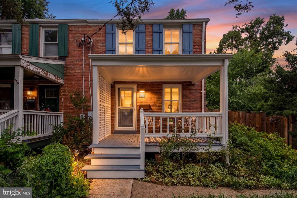 Red-brick home with blue shutters and a covered porch at dusk.