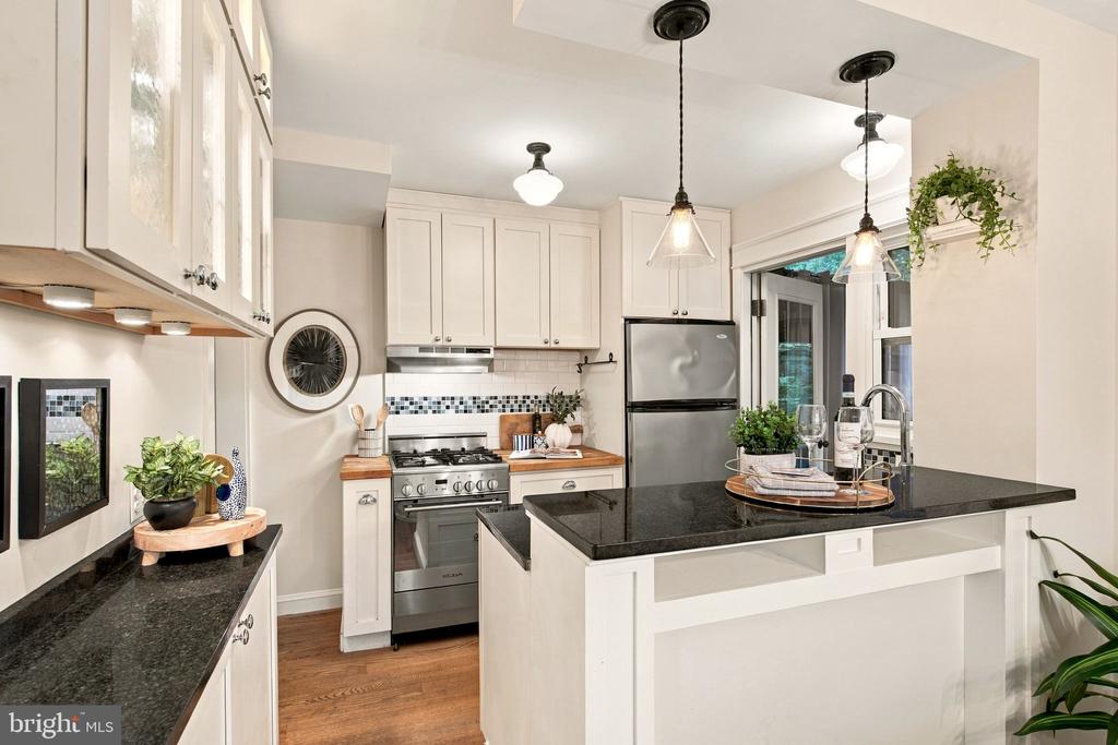 Bright kitchen with a black granite island, white cabinets, and stainless steel appliances.