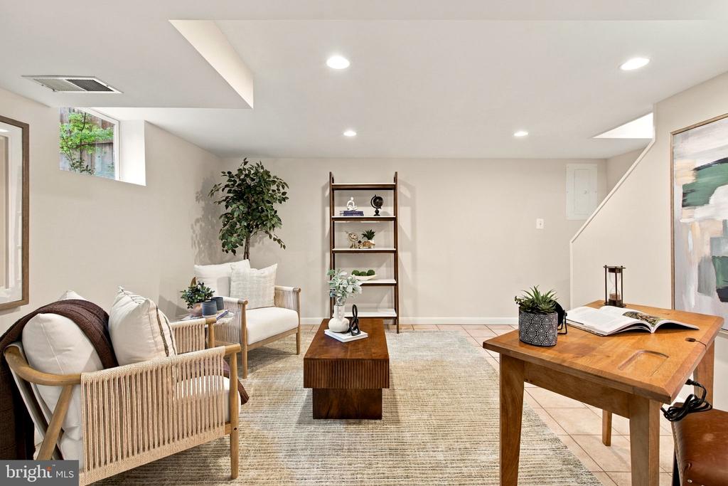 Living room with wicker armchairs, a neutral rug, and warm wood tables.