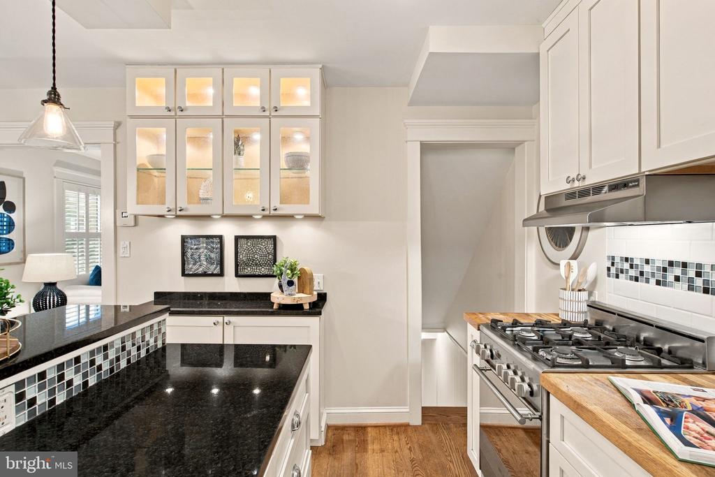Kitchen with black granite counters, white cabinetry, a gas range, and mosaic tile backsplash.