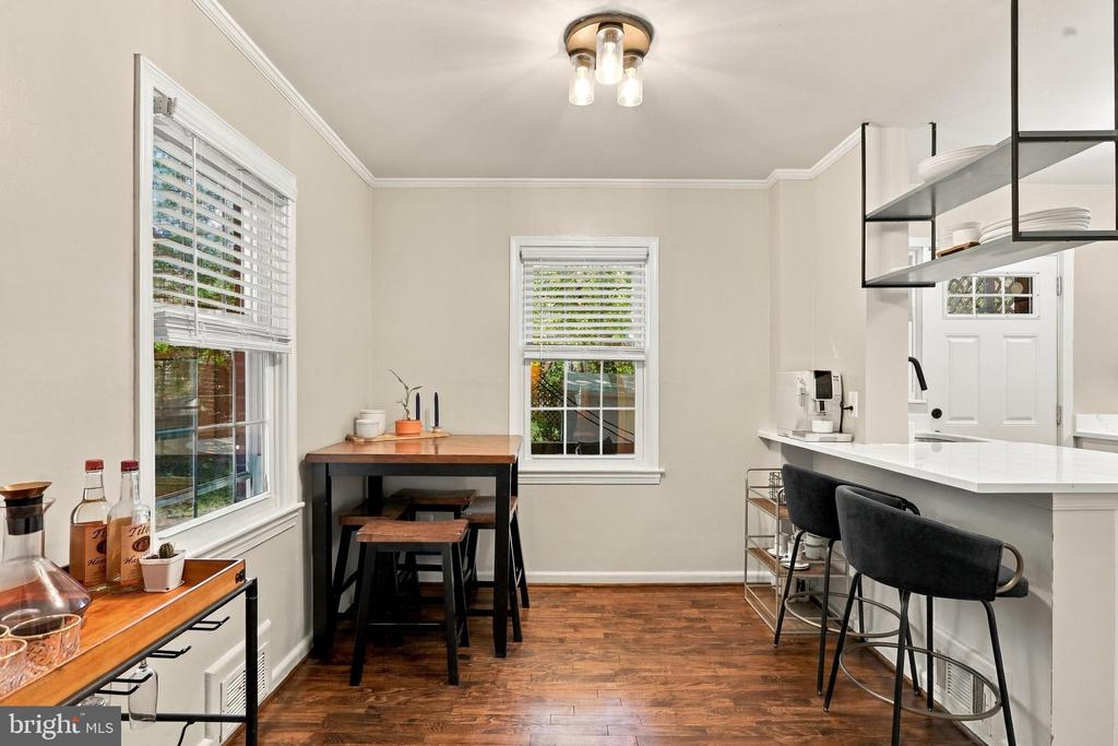 Bright kitchen with a white island, black stools, and a small dining table by the windows.