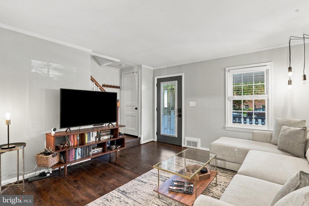 Living room with a light sectional, glass coffee table, and TV above a wooden media console.