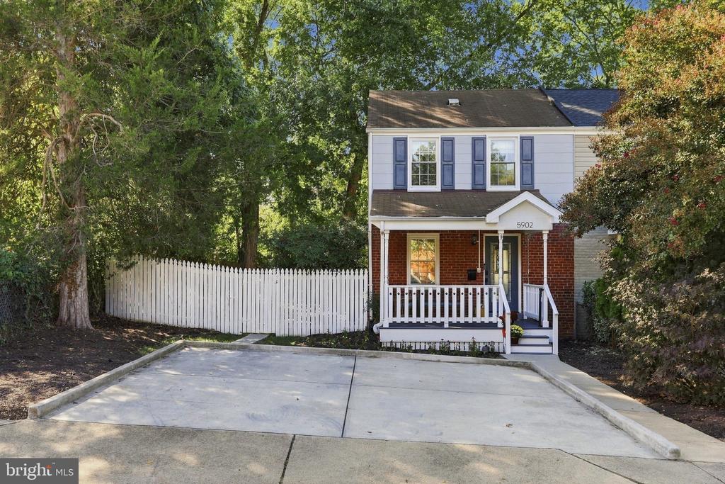 Two-story brick and siding house with blue shutters, a covered porch, and a wide concrete driveway.