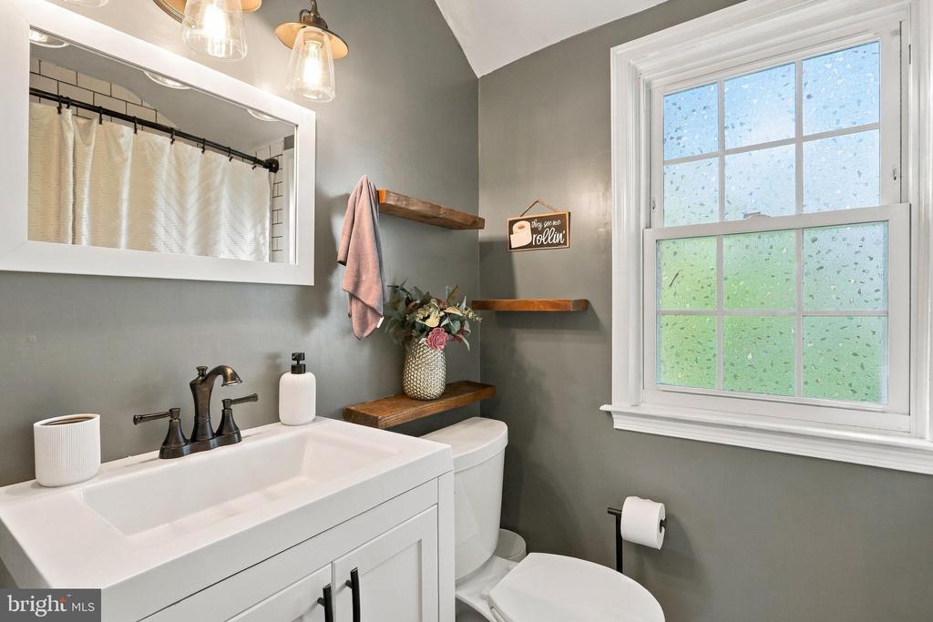 Bathroom with a white vanity, gray walls, floating wood shelves, and a large window.