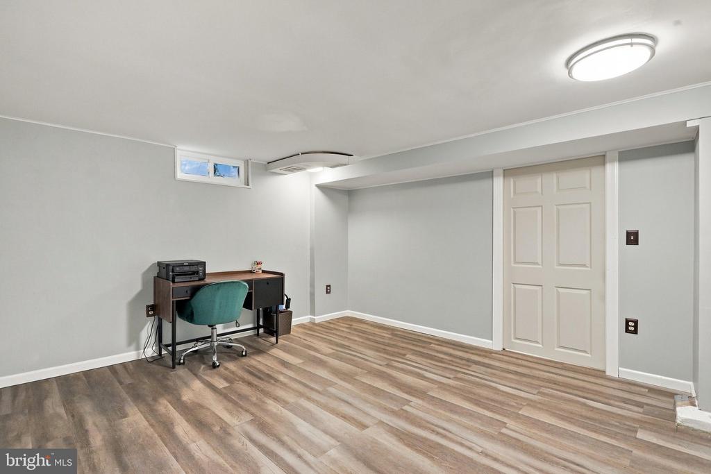Office with a desk, teal chair, gray walls, and wood-look plank flooring.