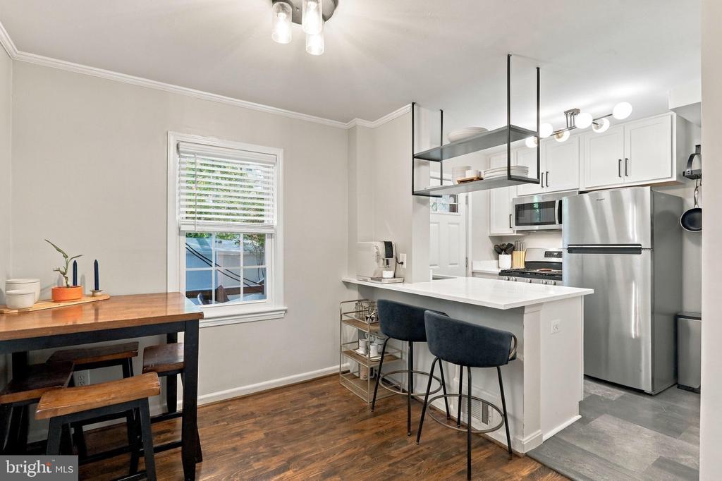 Kitchen with white island, stainless steel appliances, and a wood dining table beside the window.