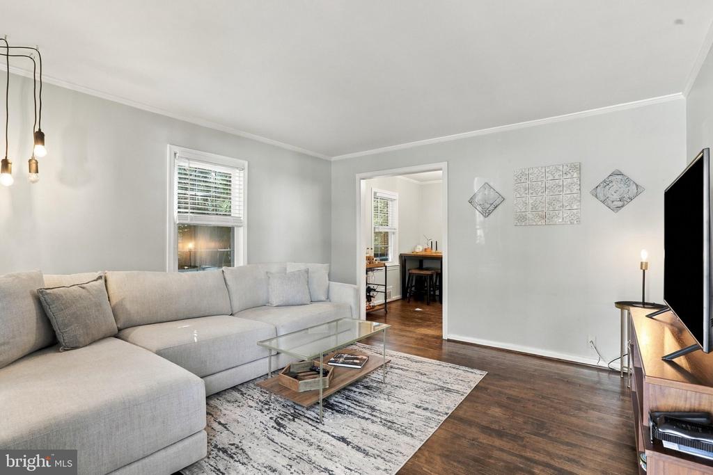 Living room with a light gray sectional, glass coffee table, and hardwood floors.