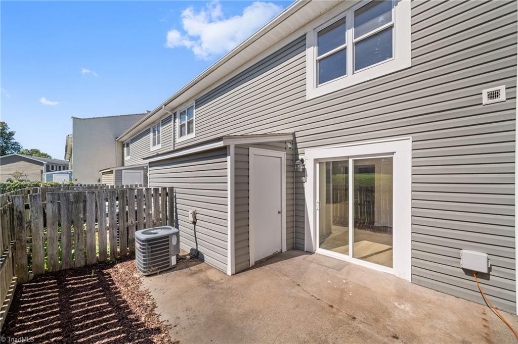 Townhouse patio with a concrete slab, sliding glass door, and fenced side area.