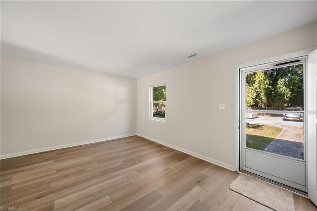 Vacant room with wood-look flooring, a small window, and a glass-paneled exterior door.