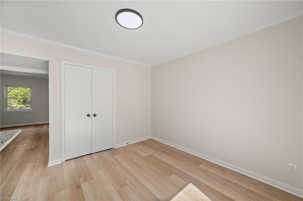 Empty room with light wood-look flooring and a white double-door closet.