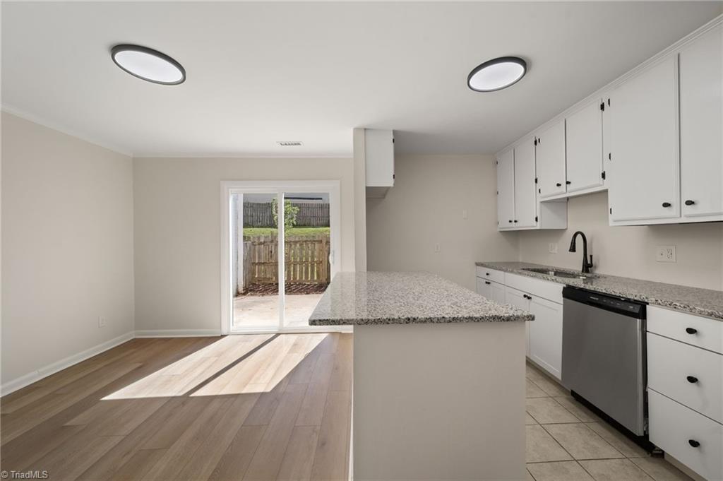 Kitchen with a large granite peninsula, white cabinetry, and sliding doors to a fenced patio.