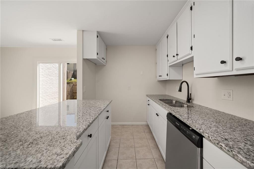 Kitchen with white cabinets, granite countertops, a double-basin sink, and stainless steel dishwasher.