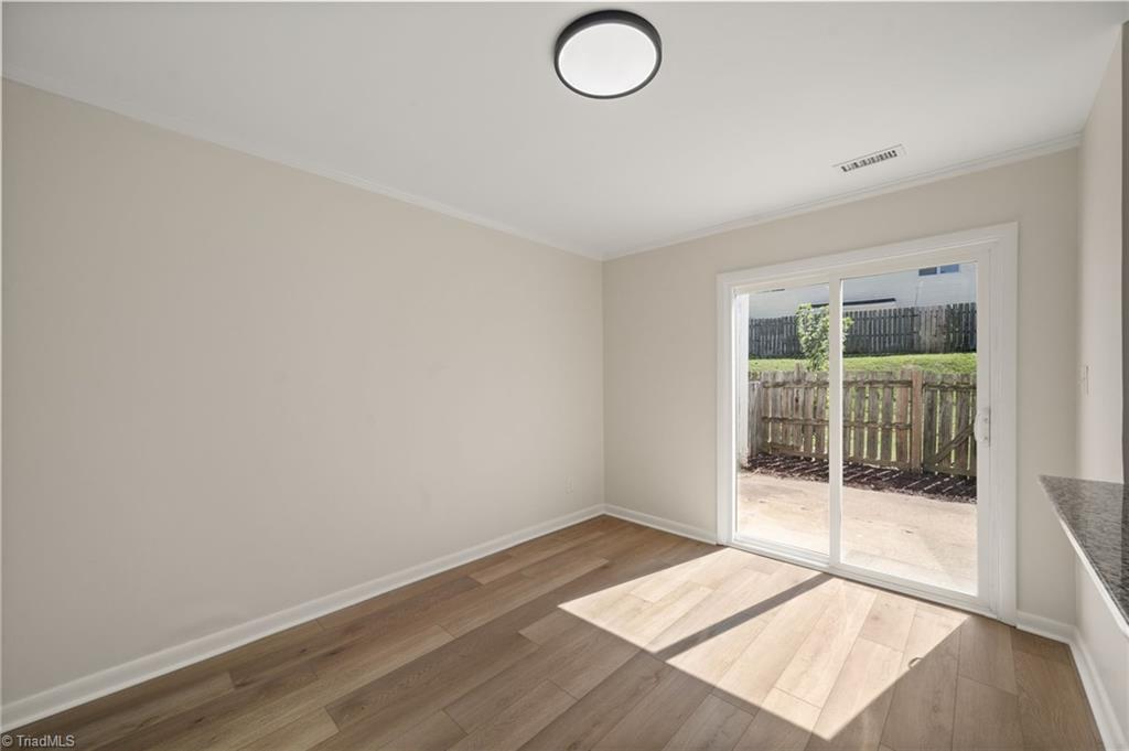 Vacant room with wood-look flooring and a sliding glass door opening to a fenced patio.