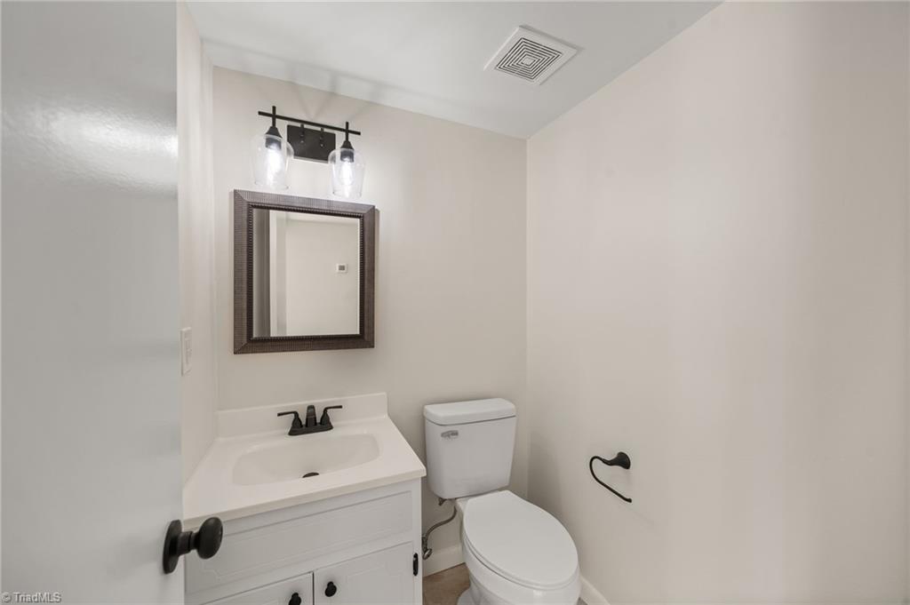Bathroom with a white vanity, framed mirror, and toilet.
