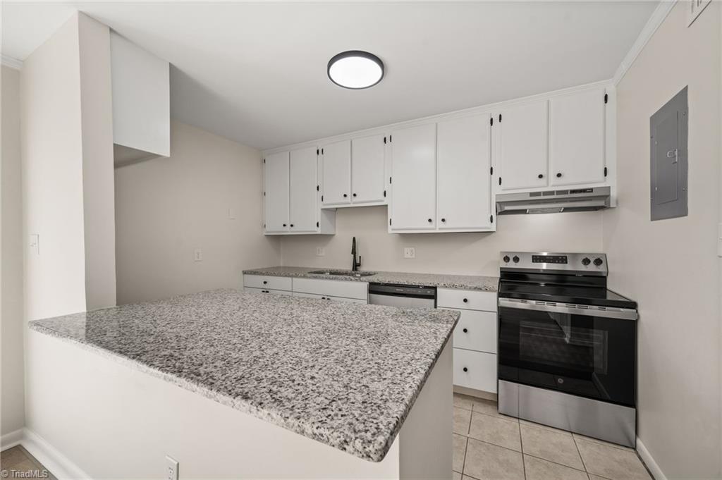 Kitchen with white cabinets, a large speckled granite peninsula, and stainless steel appliances.