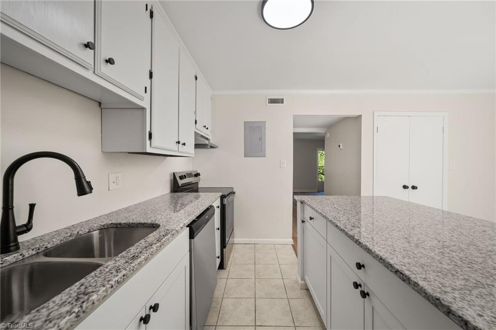 Kitchen with white cabinets, granite counters, stainless steel appliances, and a long central island.