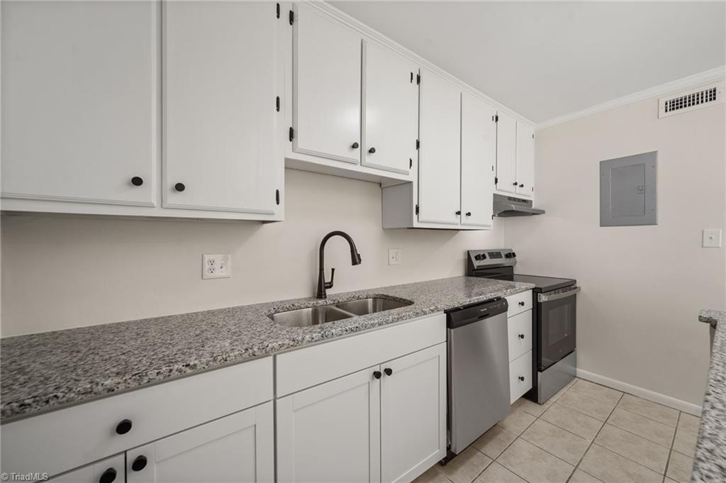 Kitchen with white cabinets, granite counters, a double sink, and stainless-steel appliances.