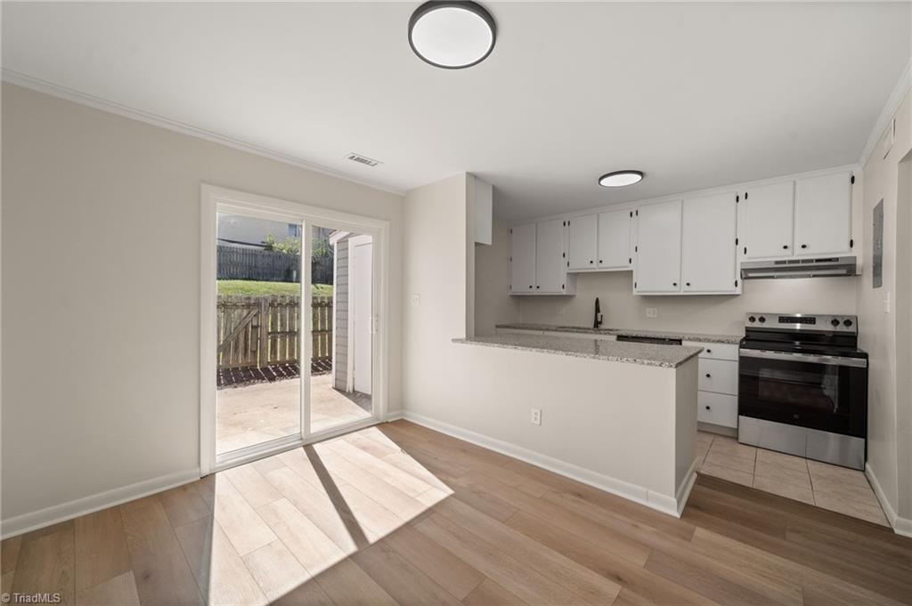 Vacant kitchen with white cabinets, a peninsula counter, and sliding glass doors to a patio.