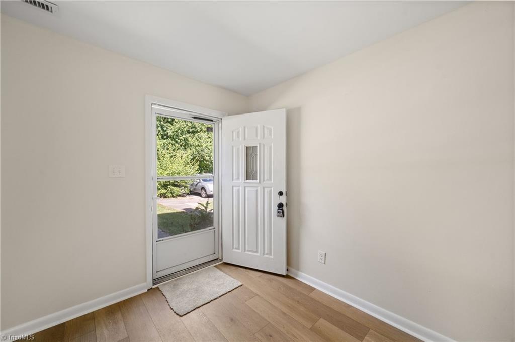 Vacant entry with wood-look flooring and an open front door beside a large glass panel.