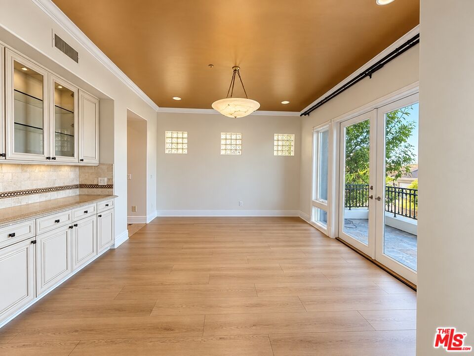 Empty dining area with built-in cabinetry, a gold-toned ceiling, and glass doors to a balcony.